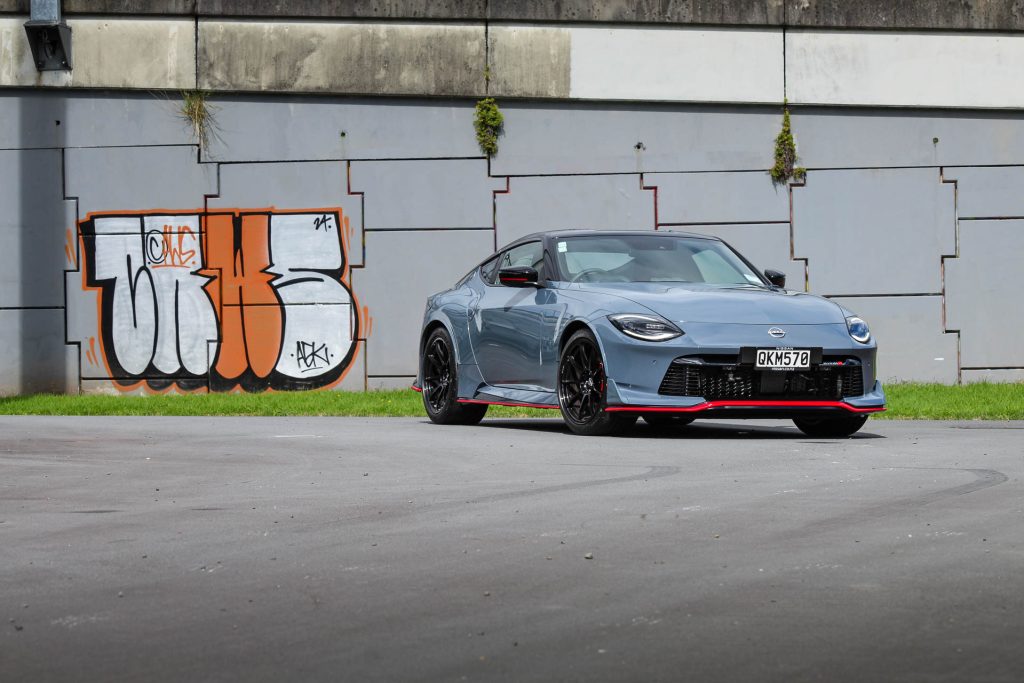 Nissan Z Nismo 400z, shown from the front quarter in front of graffiti'd wall