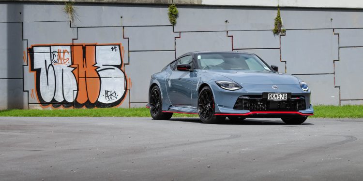 Nissan Z Nismo 400z, shown from the front quarter in front of graffiti'd wall