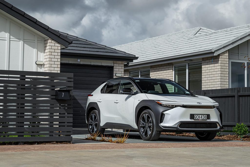 Toyota bZ4X Pure in white, parked in front of a new home