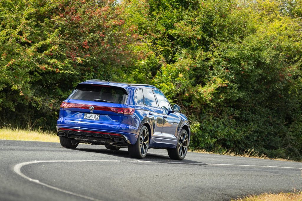 Blue Volkswagen Touareg R PHEV taking a corner at pace, shown from the rear
