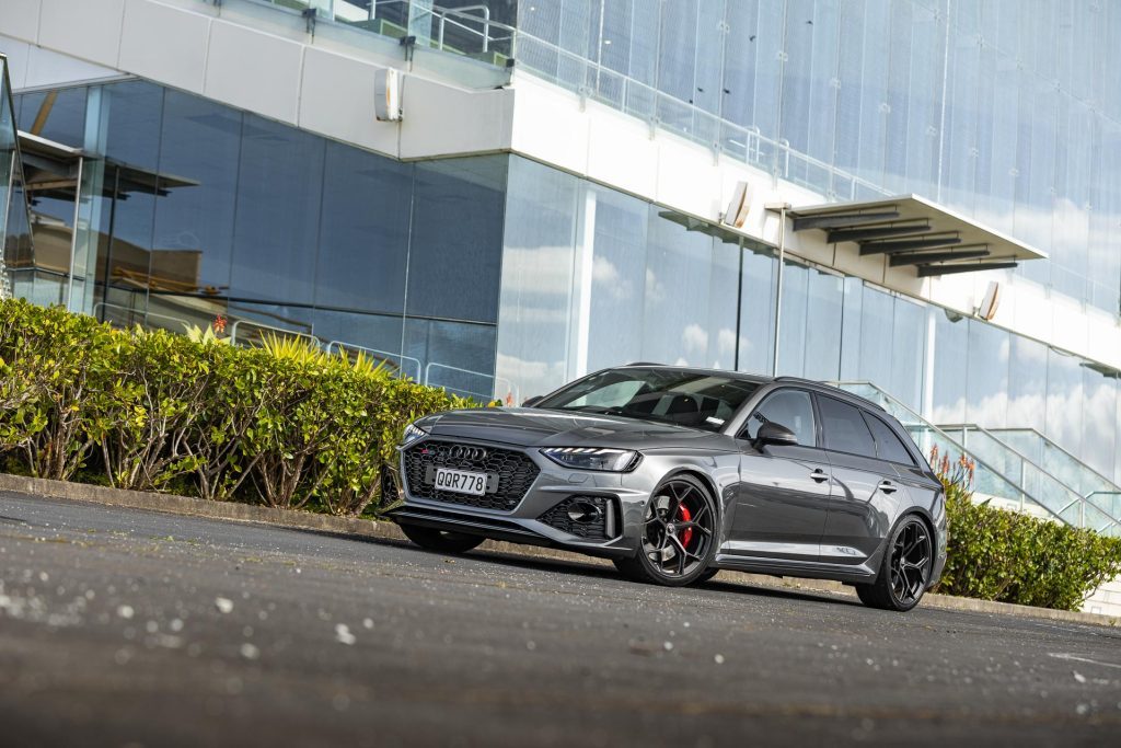 Audi RS4 Competition front quarter shot, parked in front of glass building