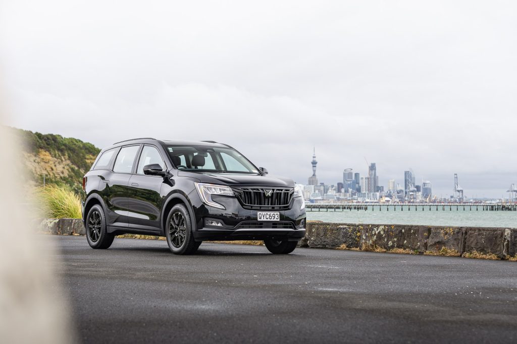 Mahindra XUV700 AX7L in black, parked in front of Auckland's skyline