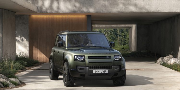 Defender in green outside a house on concrete