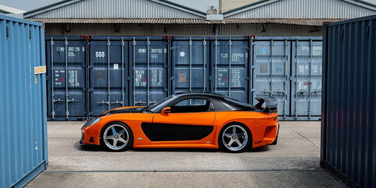 Fast and Furious Mazda RX-7 in orange in front of blue containers